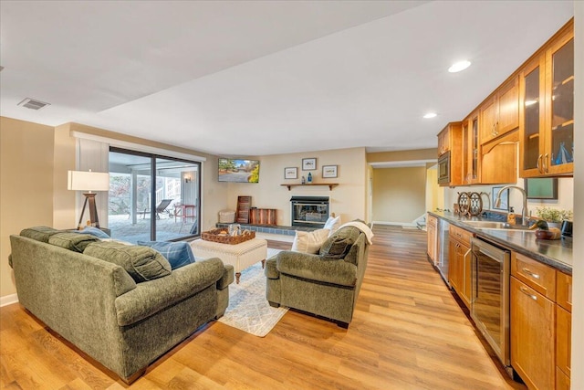 living room featuring light wood-type flooring, visible vents, recessed lighting, baseboards, and a tile fireplace