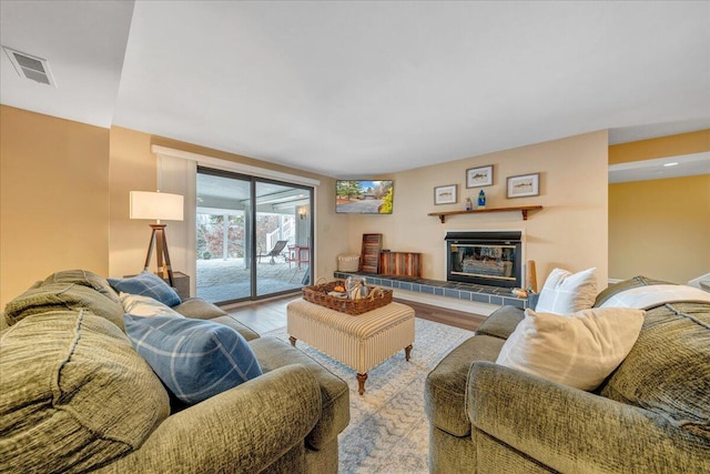 living room with wood finished floors, visible vents, and a tile fireplace