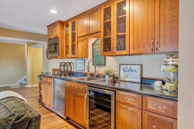 kitchen with a sink, brown cabinets, appliances with stainless steel finishes, and beverage cooler