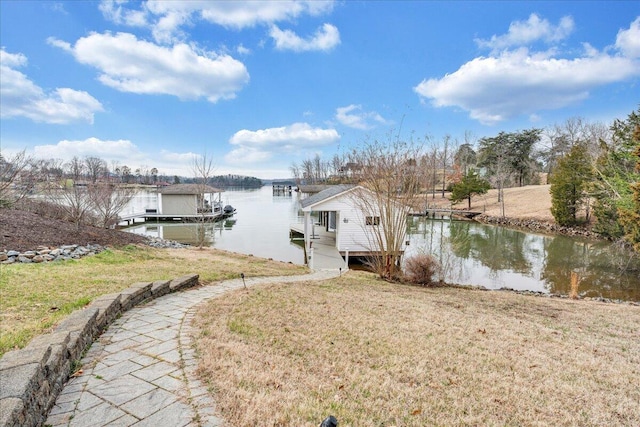 dock area with boat lift, a lawn, and a water view