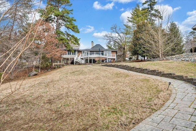 view of front of home with a deck, a front lawn, stairs, and a chimney