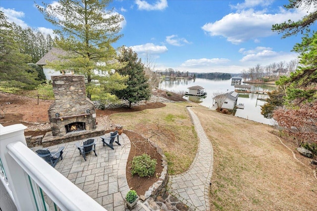 view of yard featuring a water view, an outdoor stone fireplace, and a patio area