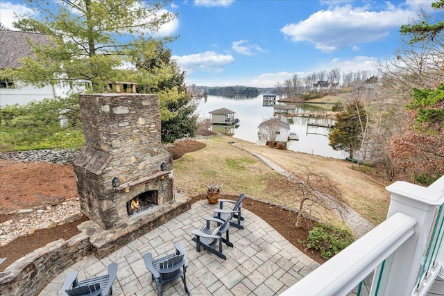 view of patio / terrace featuring a water view and an outdoor stone fireplace