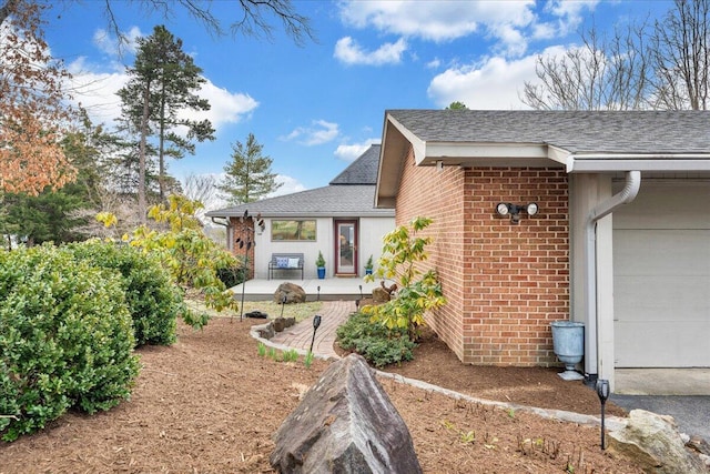 view of property exterior featuring a patio area, brick siding, and roof with shingles