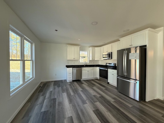 kitchen featuring appliances with stainless steel finishes, white cabinetry, dark wood finished floors, and baseboards