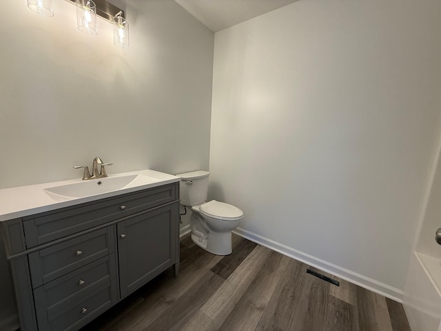 bathroom with visible vents, toilet, vanity, wood finished floors, and baseboards