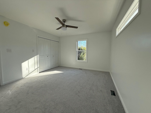 unfurnished bedroom featuring a ceiling fan, a closet, light carpet, and baseboards