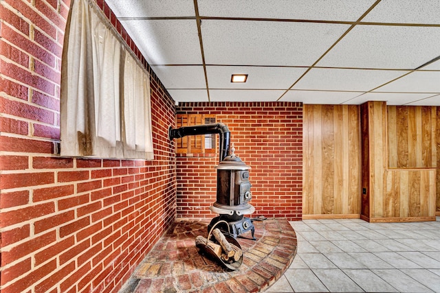 details with wooden walls, a drop ceiling, and a wood stove