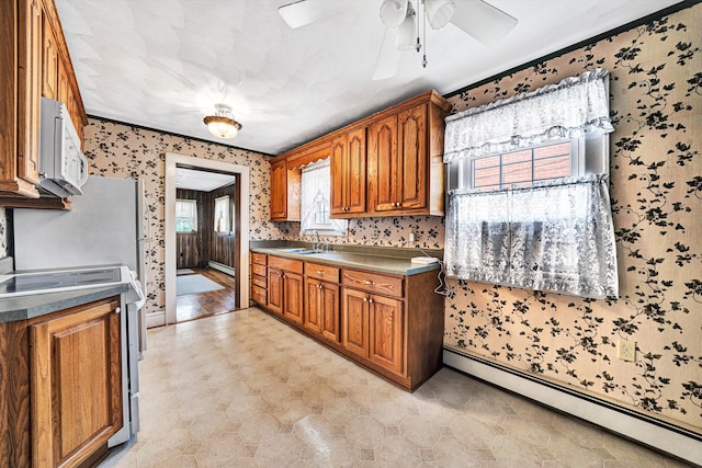 kitchen with ceiling fan, sink, white appliances, and baseboard heating