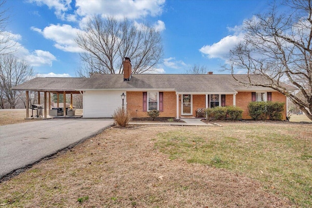 ranch-style home with aphalt driveway, an attached carport, brick siding, a chimney, and a front yard