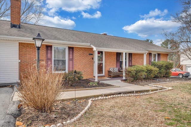 single story home featuring brick siding, a chimney, and roof with shingles