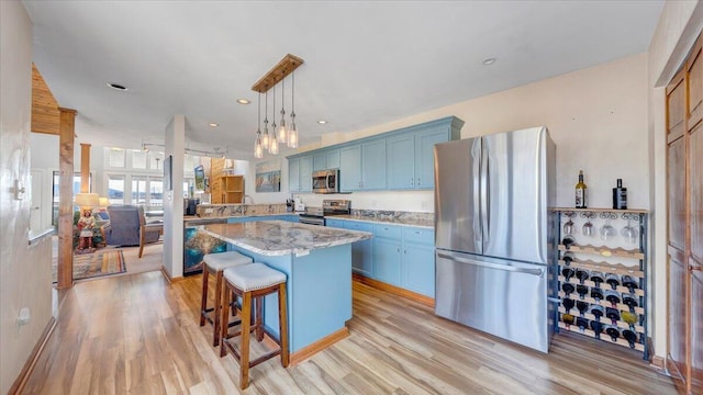 kitchen with light hardwood / wood-style flooring, blue cabinetry, a kitchen island, stainless steel appliances, and a breakfast bar area