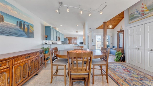 dining space featuring rail lighting and vaulted ceiling