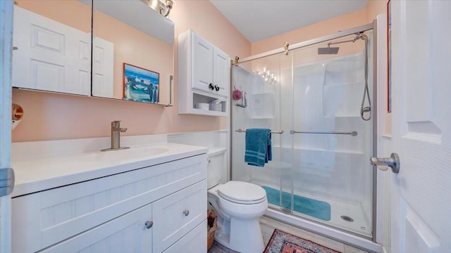 bathroom with toilet, vanity, and a shower with shower door