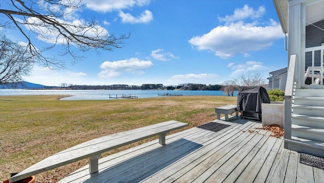 wooden deck featuring a water view, a lawn, and grilling area