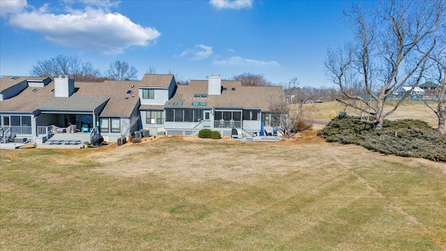 rear view of house featuring a lawn and a sunroom