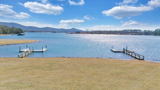 view of dock featuring a water and mountain view and a lawn