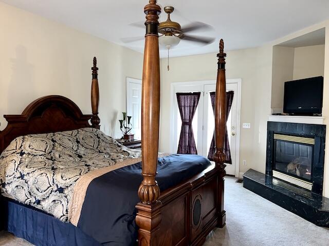 bedroom featuring a fireplace, light colored carpet, and ceiling fan