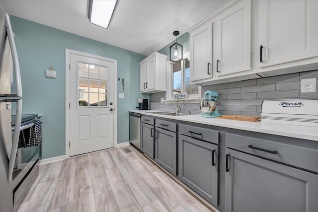 kitchen featuring gray cabinets, decorative light fixtures, sink, white cabinets, and stainless steel appliances