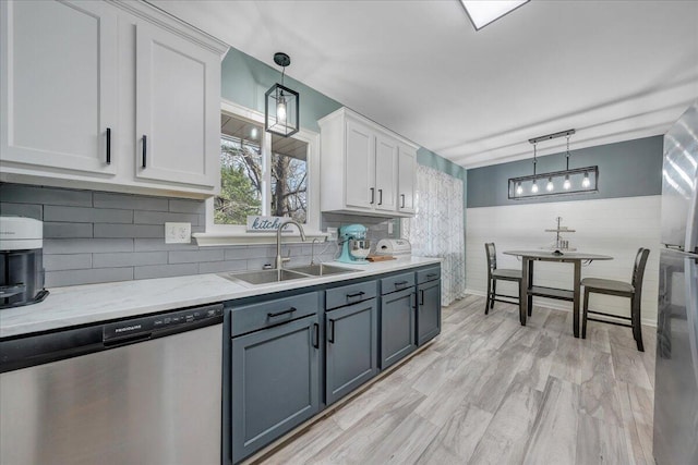 kitchen with sink, appliances with stainless steel finishes, hanging light fixtures, light hardwood / wood-style floors, and white cabinets