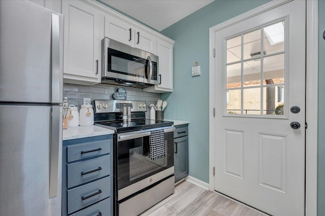 kitchen featuring white cabinetry, stainless steel appliances, decorative backsplash, and light hardwood / wood-style flooring