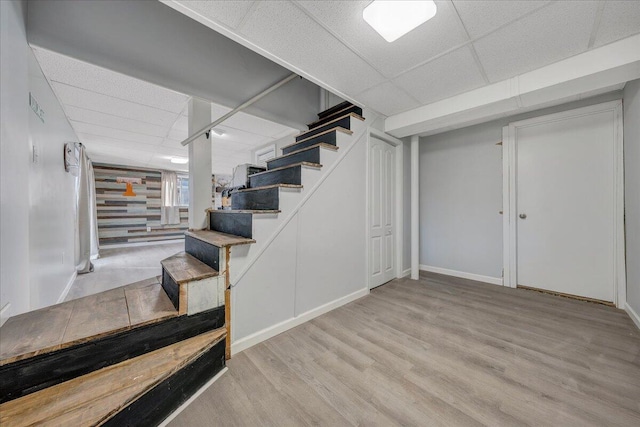 basement featuring a drop ceiling and light wood-type flooring