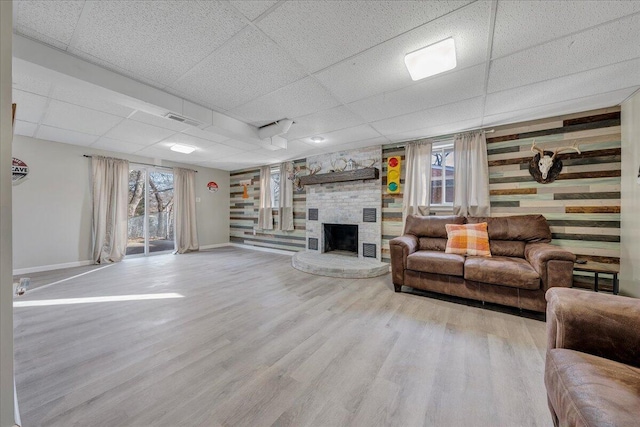 living room featuring a fireplace, wood-type flooring, and a paneled ceiling