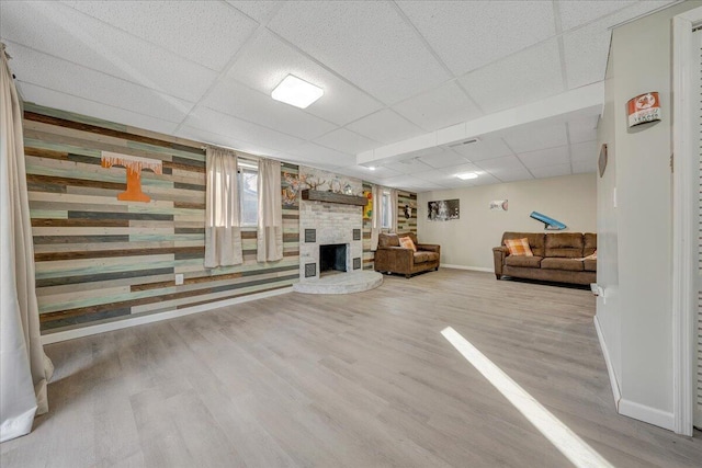 unfurnished living room featuring a large fireplace, a paneled ceiling, and light hardwood / wood-style floors