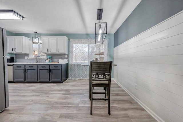 kitchen with gray cabinets, pendant lighting, sink, white cabinets, and light wood-type flooring