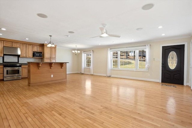 kitchen with black microwave, a breakfast bar area, ornamental molding, decorative backsplash, and stainless steel range with electric stovetop