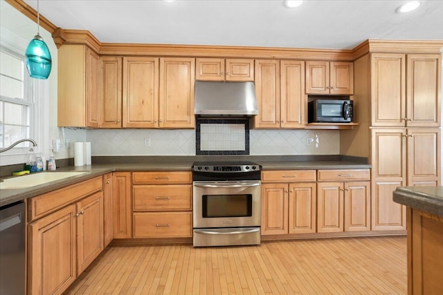 kitchen featuring under cabinet range hood, stainless steel appliances, a sink, dark countertops, and decorative light fixtures