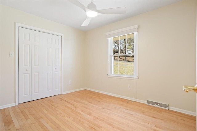 unfurnished bedroom with baseboards, visible vents, a ceiling fan, light wood-style flooring, and a closet