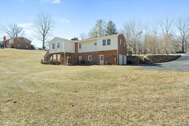 back of house with brick siding, a lawn, and an attached garage