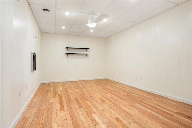 spare room featuring a paneled ceiling, visible vents, a ceiling fan, baseboards, and light wood finished floors