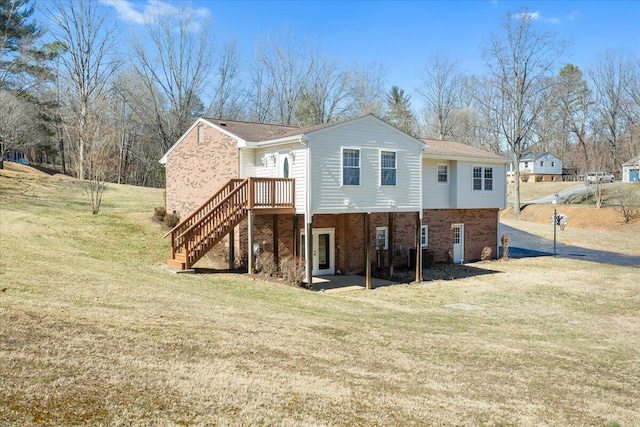 back of house with brick siding, a lawn, and stairs