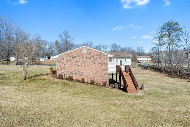 view of side of property featuring brick siding and a yard