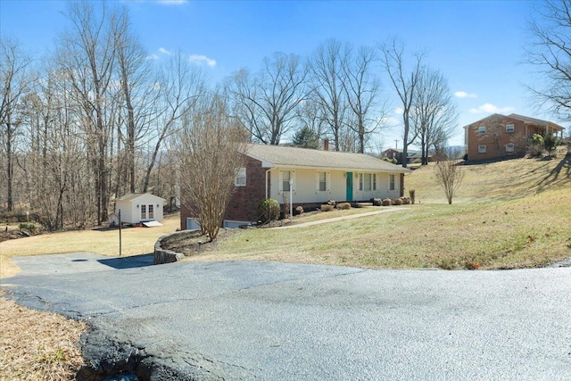 ranch-style house featuring an outdoor structure, driveway, a chimney, and a front lawn