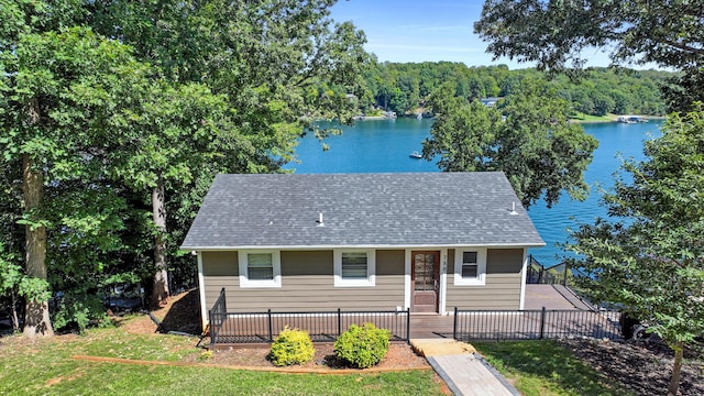 view of front of house featuring a front lawn, fence, a water view, and a shingled roof