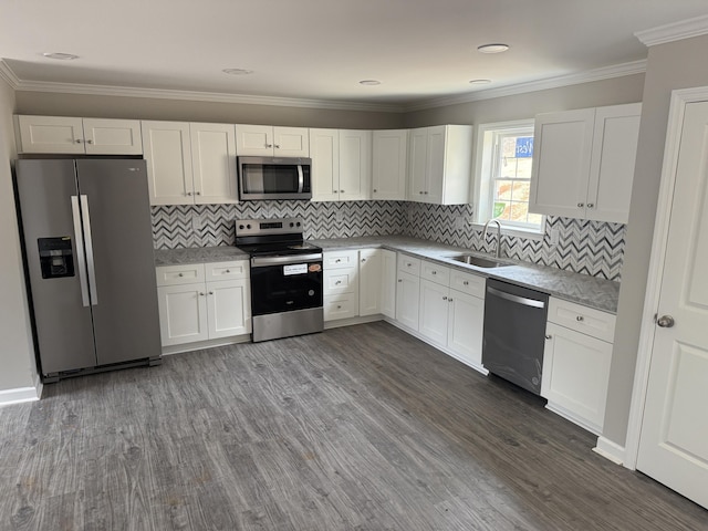 kitchen featuring dark wood-style floors, a sink, ornamental molding, stainless steel appliances, and white cabinets