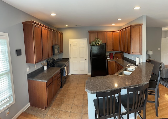 1057 Barrow Hills Dr, Huddleston, VA 24104 - kitchen featuring black appliances, a sink, a breakfast bar area, a peninsula, and brown cabinets