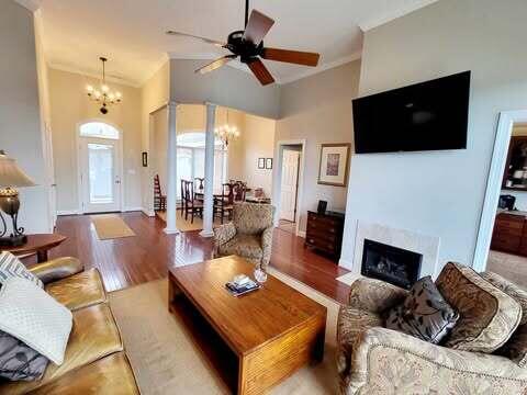 living room featuring a high ceiling, crown molding, dark hardwood / wood-style floors, and ceiling fan with notable chandelier