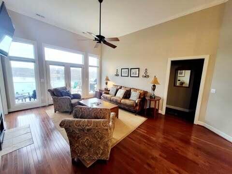 living room with ceiling fan, a towering ceiling, and dark hardwood / wood-style flooring