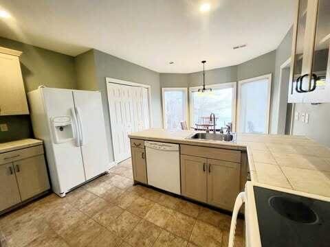 kitchen featuring sink, white appliances, and hanging light fixtures