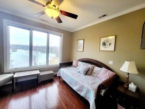 bedroom with dark hardwood / wood-style flooring, ornamental molding, ceiling fan, and a water view