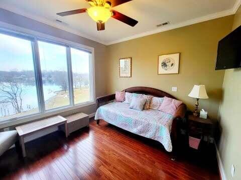 bedroom featuring hardwood / wood-style floors, ornamental molding, and ceiling fan