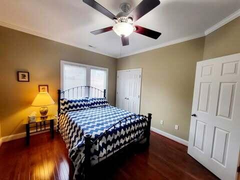 bedroom with ornamental molding, dark hardwood / wood-style floors, ceiling fan, and a closet