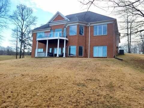 back of house featuring a balcony and a yard