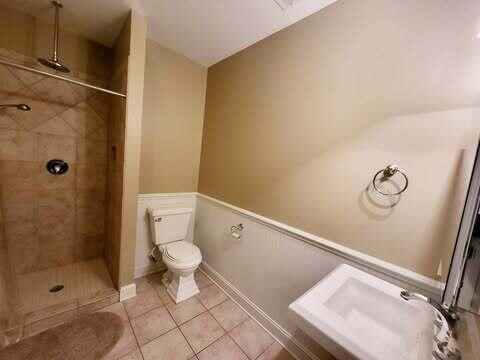 bathroom featuring tile patterned flooring, sink, a tile shower, and toilet