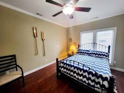 bedroom featuring dark wood-type flooring, ornamental molding, and ceiling fan