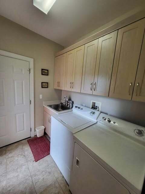 washroom with sink, light tile patterned floors, washer and clothes dryer, and cabinets